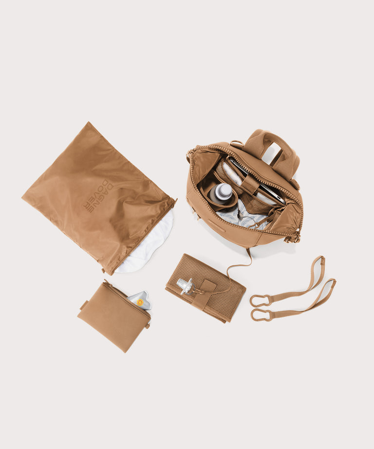 Collection of brown travel bags and accessories on a light beige background