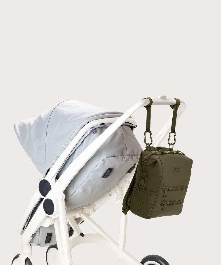 Green backpack attached to a white stroller on a light gray background