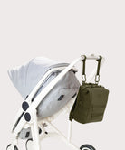 Green backpack attached to a white stroller on a light gray background