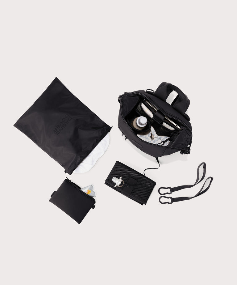 Black travel bag with accessories on a light gray background