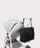 Black diaper bag attached to a stroller on a light gray background