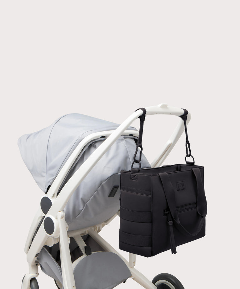 Black diaper bag attached to a stroller on a light gray background