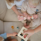 Children playing with wooden shape sorting toy on a couch