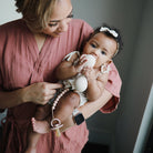 Woman holding a baby wearing a pink outfit with a teething ring.