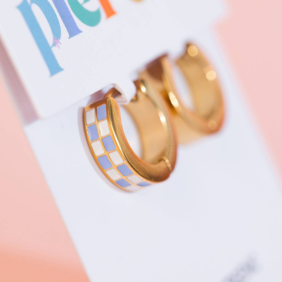 Gold hoop earrings with a geometric pattern on a colorful background