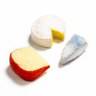 Three miniature felt cheese pieces on a white background: a round white cheese with a yellow center and a cut slice, a wedge with a red exterior and pale yellow center, and a triangular blue-and-white marbled cheese piece.