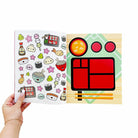 Sheet of colorful stickers featuring sushi and Japanese food items held by a hand.