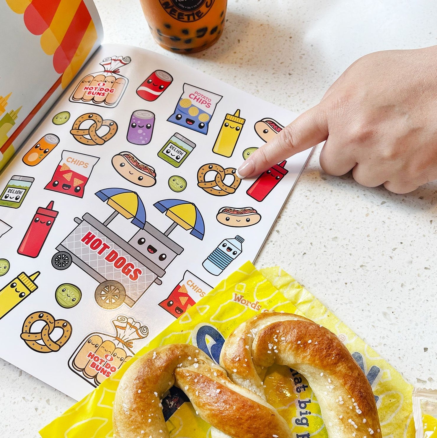 Person cutting a pretzel with a book of stickers in the background