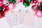 Sheet of decorative stickers with colorful border on a white background surrounded by Christmas ornaments.