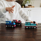 Child playing with toy trains on a wooden table