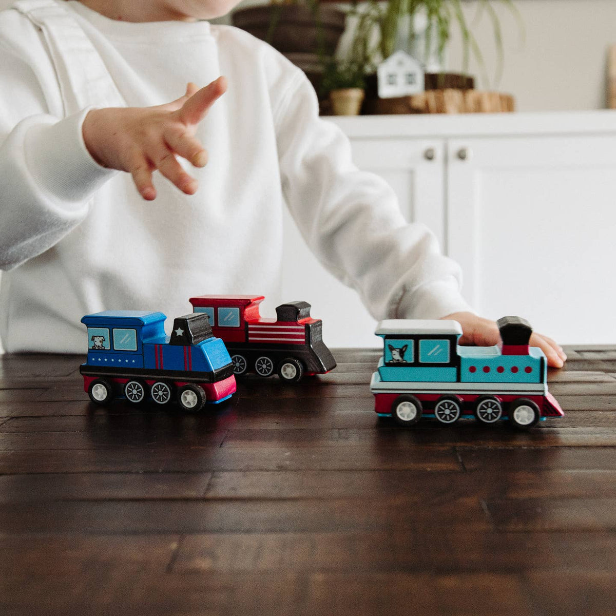 Child playing with toy trains on a wooden table