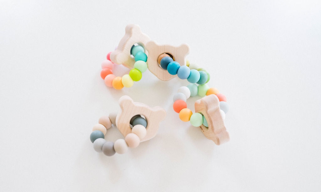 Colorful baby teething ring with star-shaped wooden elements on a white background