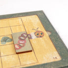 Wooden toy with a caterpillar design on a checkered surface