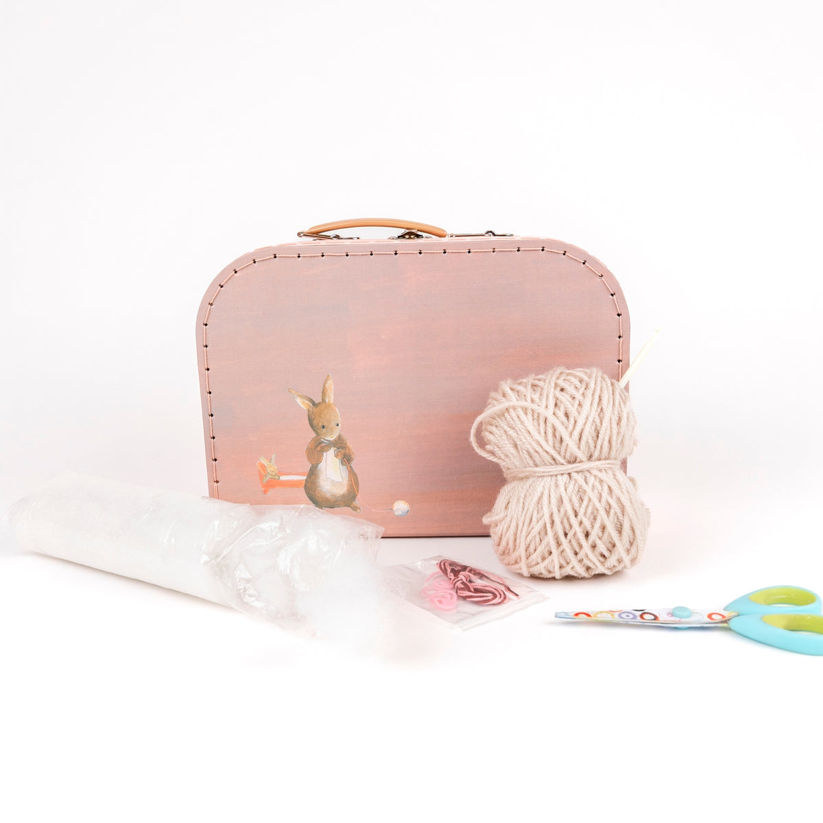 Pink sewing kit with a ball of yarn, scissors, and a rabbit figure on a white background