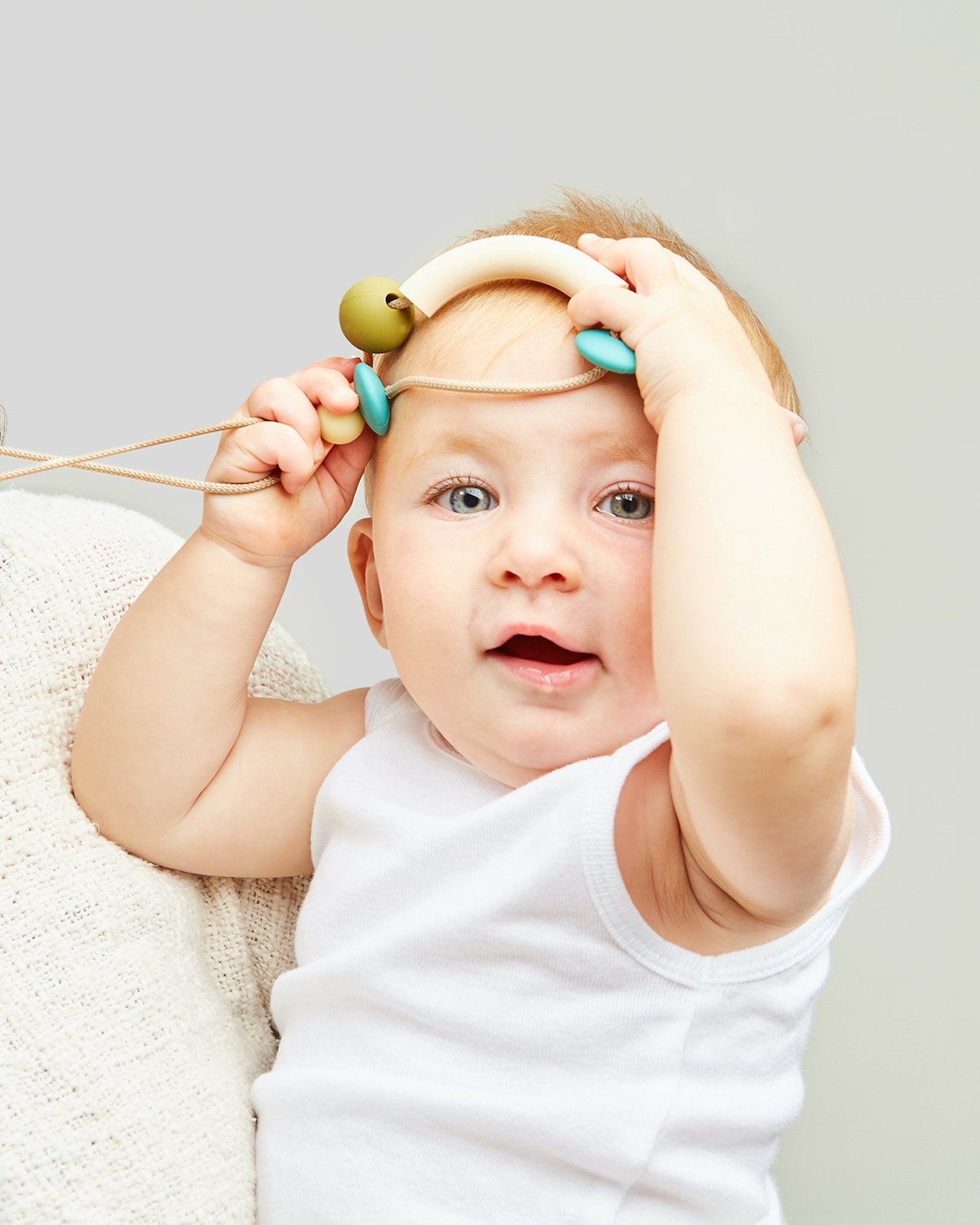 Baby playing with a toy on a plain background