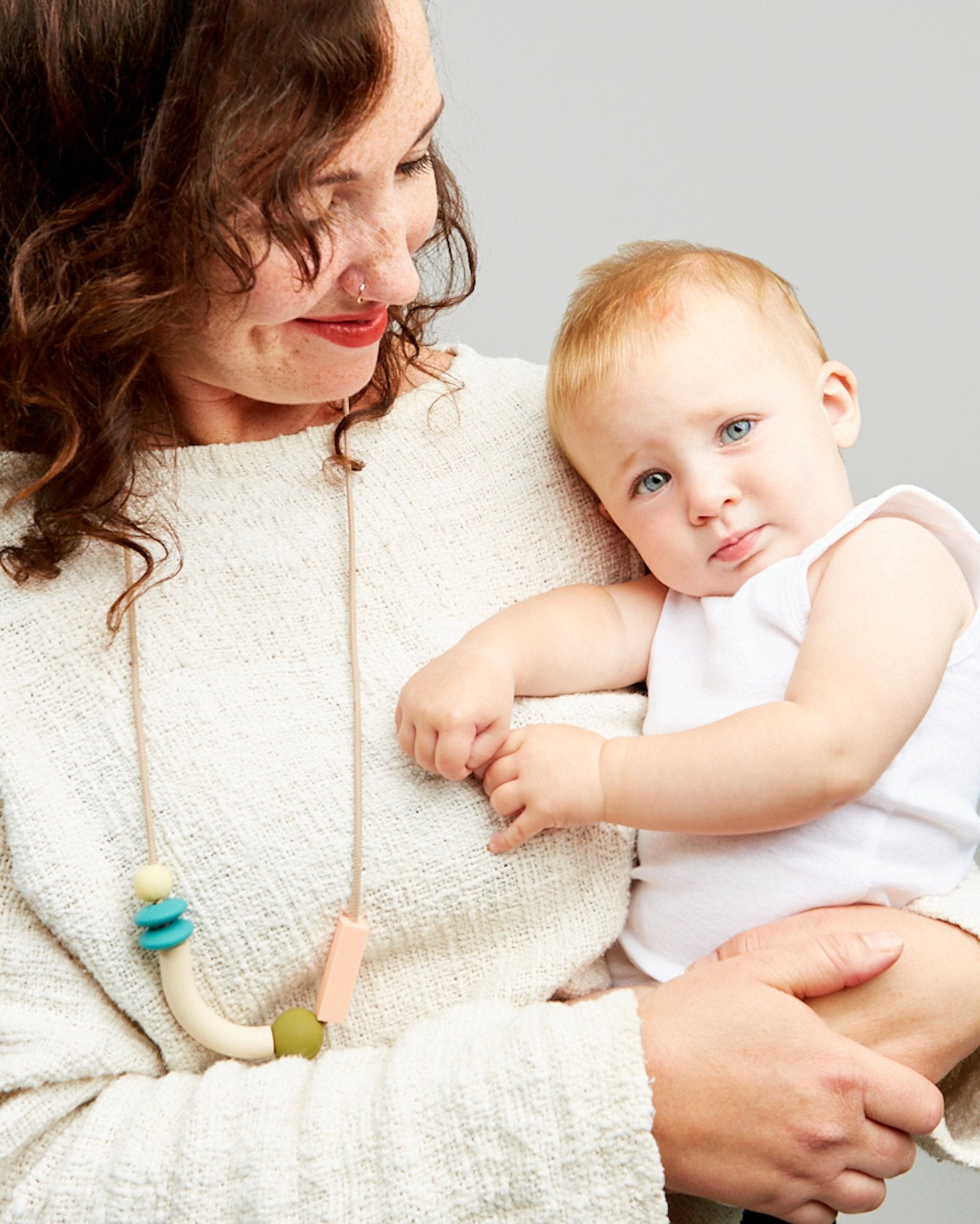 Woman holding a baby against a plain background