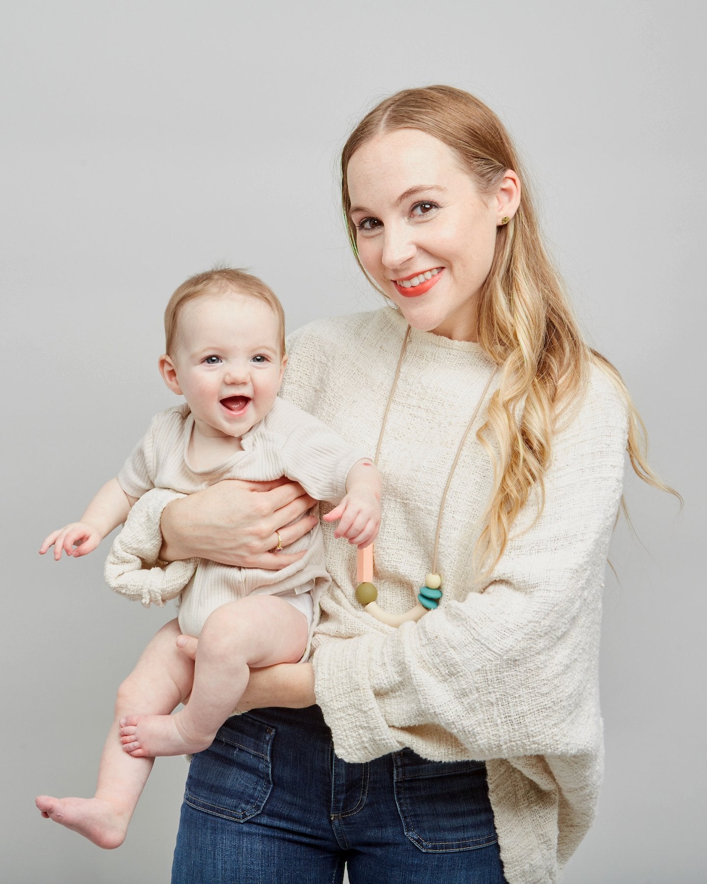 Woman holding a baby against a plain background