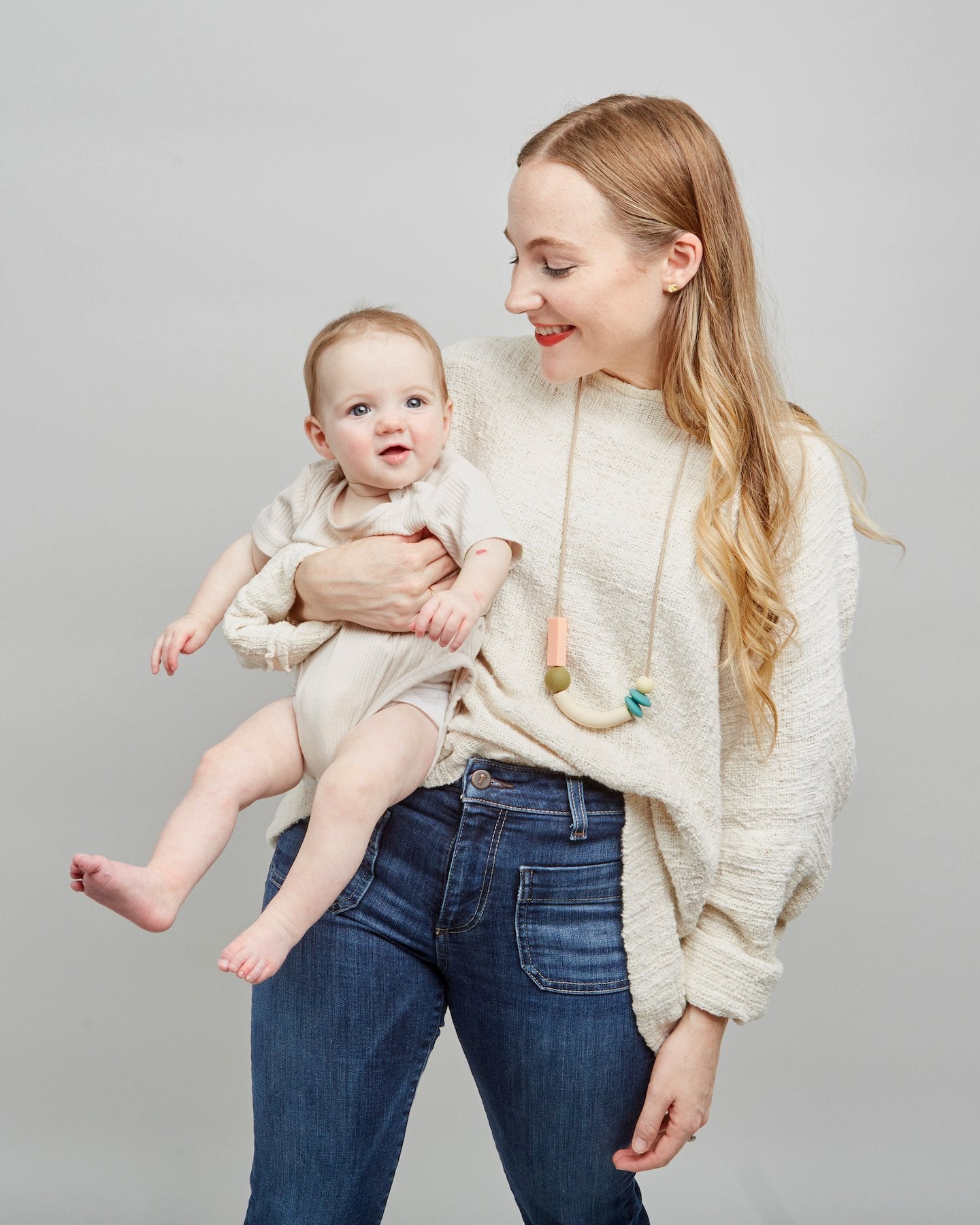 Woman holding a baby against a plain background