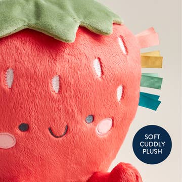 Plush strawberry toy with a smiley face on a light gray background