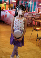Young girl holding a small round object in a room with colorful walls and wooden floor.
