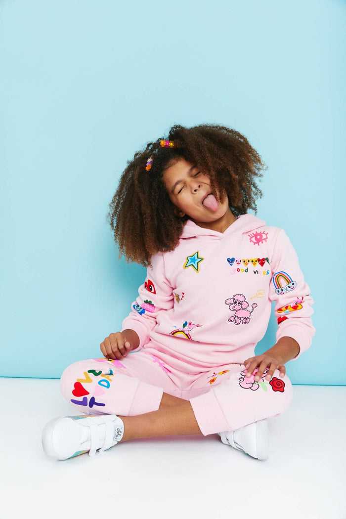 Child wearing a pink outfit with colorful patches against a light blue background