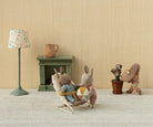Miniature scene with stuffed animals in a room setting, including a lamp, fireplace, and decorative items.