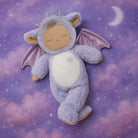 Plush toy dragon with closed eyes on a purple cloud background