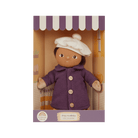 Doll in a purple coat and white hat in a box with a green background