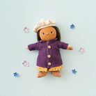Toy figure wearing a purple coat and yellow dress on a light blue background with decorative flowers.
