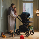Woman pushing a black stroller with a child in a room.