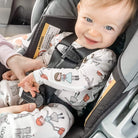 Child in a car seat with a visible brand label, sitting in a vehicle.