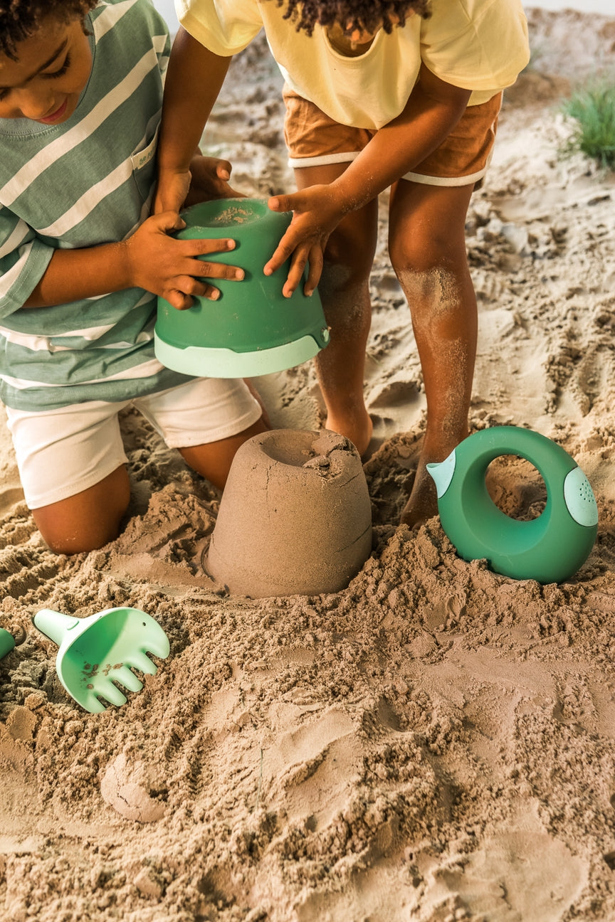 Two children playing with sand toys on a sandy surface