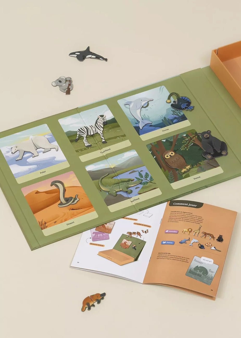 An educational children's animal puzzle book set displayed on a light beige background, featuring a green book with animal-themed cards, small animal cutout pieces, an orange booklet, and a partial orange box.