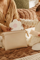 Woman and child interacting with a cloud-shaped pouch on a textured surface