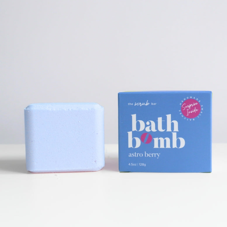 A light blue scrub bar next to its blue packaging box on a white surface against a light gray background. The box is labeled 'bath bomb' and 'astro berry' with a pink 'Super Fresh' badge.