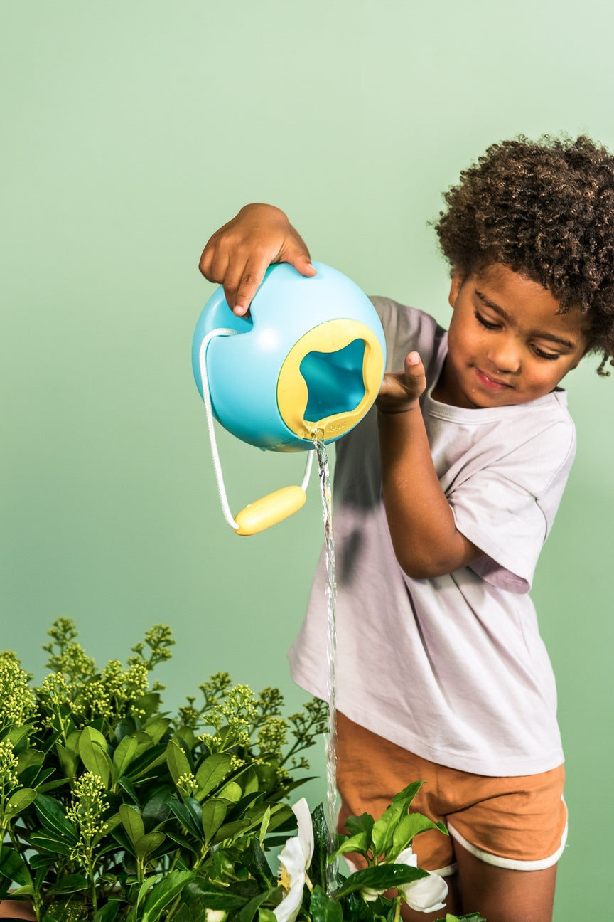 Child watering plants with a blue watering can against a green background