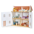 A lifestyle product photo of a large wooden dollhouse with open front doors, fully furnished with various miniature wooden furniture sets across its multiple rooms.