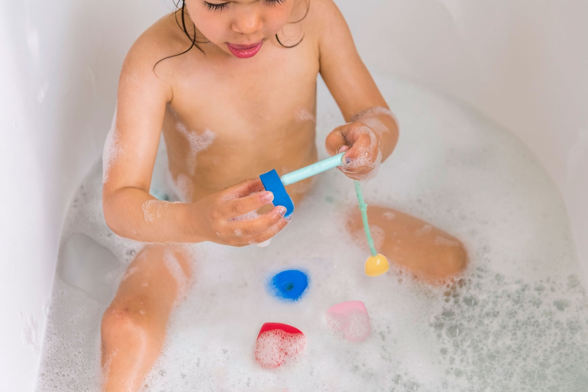 Child playing with bath toys in a bathtub filled with bubbles