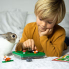 Child playing with a toy set on a bed next to a rabbit
