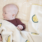 Baby lying on a textured surface with lemon-patterned blanket