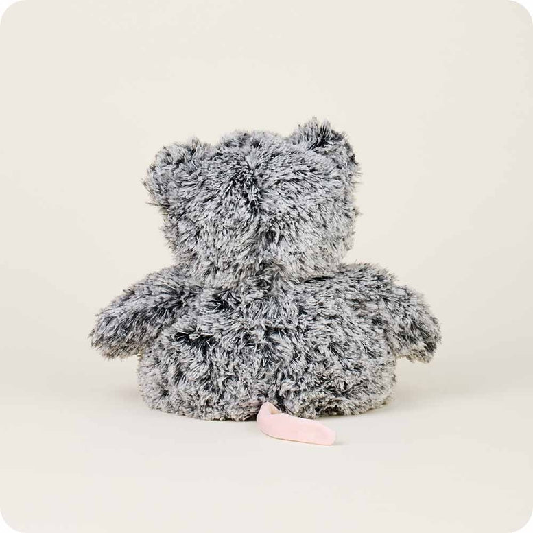 The back view of a gray and white fluffy Opossum by Warmies stuffed animal, showing its textured fur and a short pink tail extending out against a neutral background.