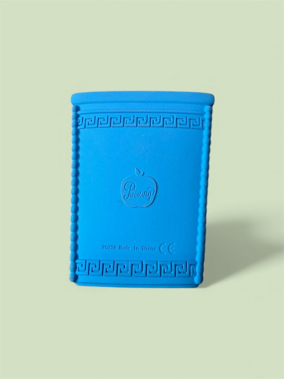 Blue textured book-shaped object with a brand logo on a light green background