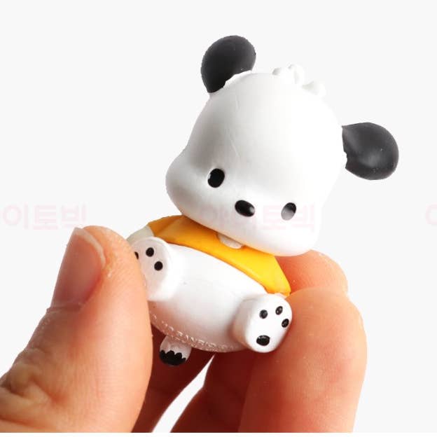 Small panda figurine with a yellow object held between fingers on a white background