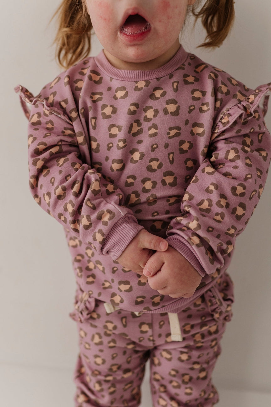 Child wearing a purple leopard print outfit against a plain background