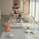 Children playing with toys on a rug in a modern room.