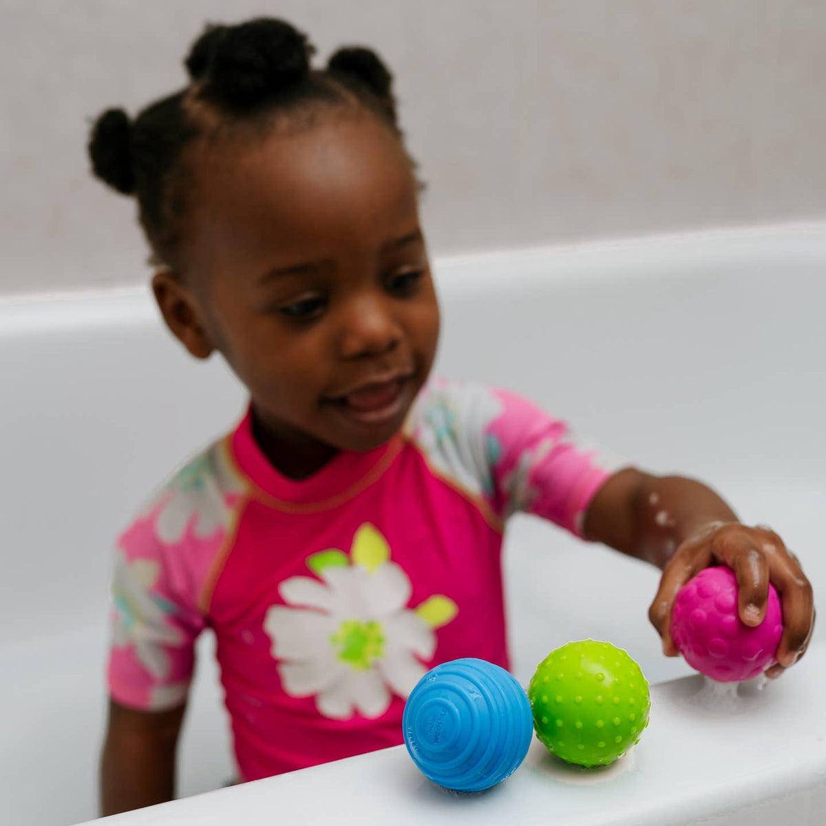 Child playing with colorful bath toys in a bathtub