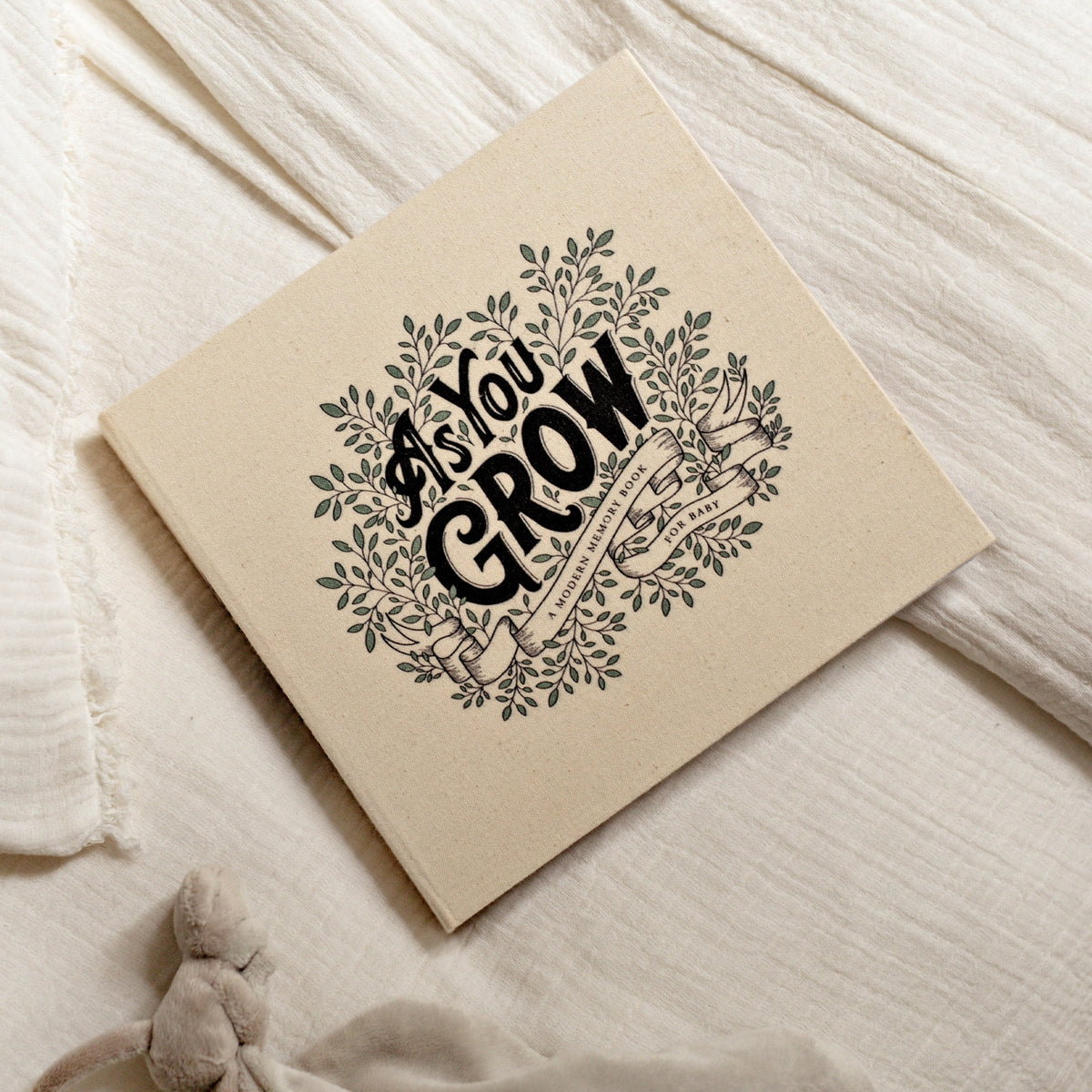 Notebook with 'As You Grow' text on a soft fabric background