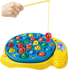 A hand holding a fishing rod over a yellow Let's Go Fishin' game board filled with colorful toy fish.