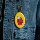 Yellow oval keychain with cartoon character on a blue denim jacket.