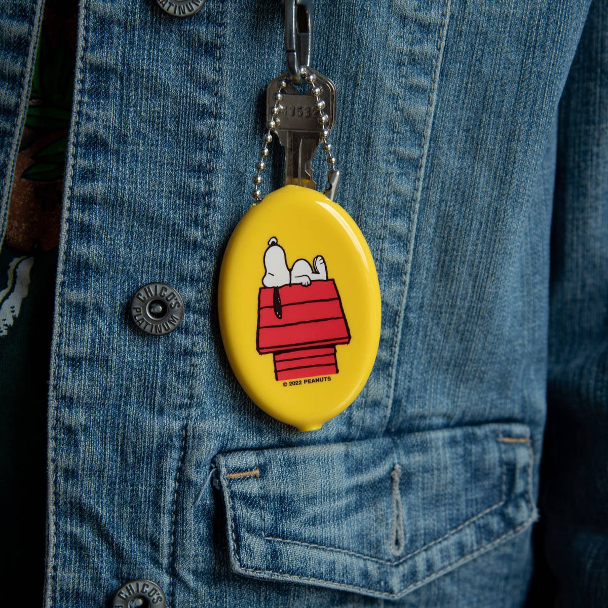 Yellow oval keychain with cartoon character on a blue denim jacket.